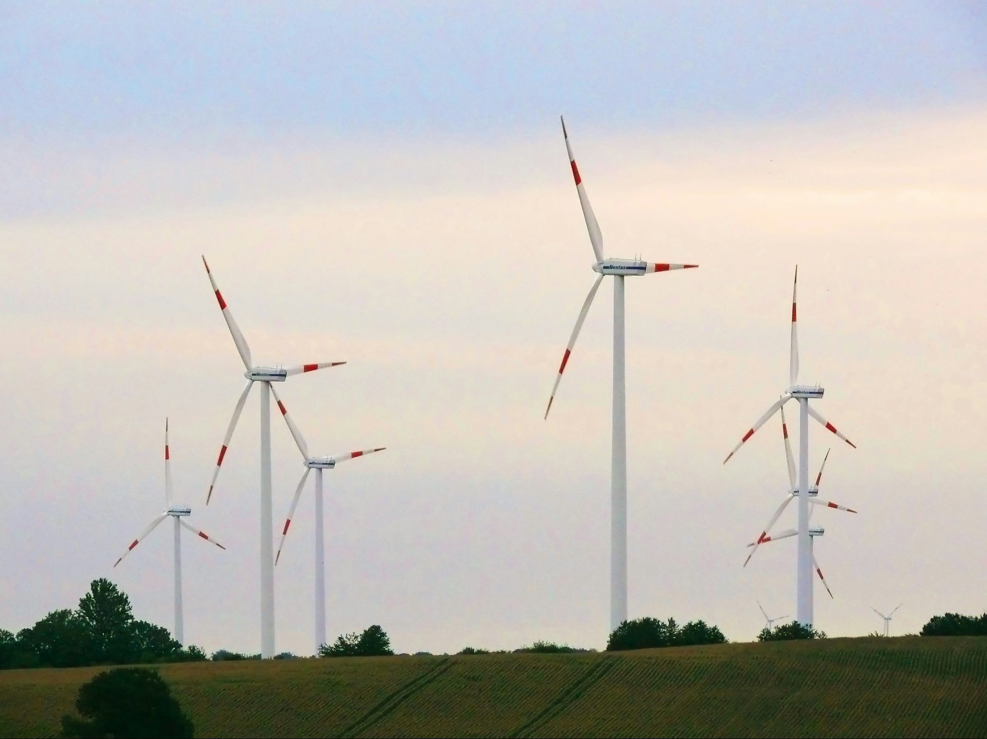 Wind turbines on a grassy hill under a cloudy sky